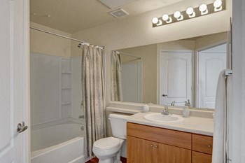 A bathroom with a wide mirror and overhead lighting Property Image