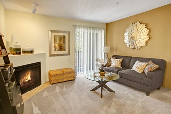 Living room with couch, coffee table, fireplace, and sliding glass door leading out to the balcony Allegro Living Room - Photo Gallery 2