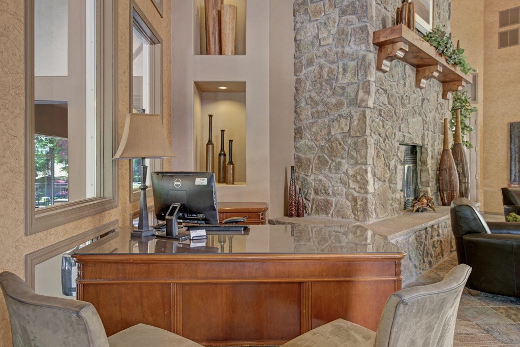 a desk with a computer in a living room with a stone fireplace