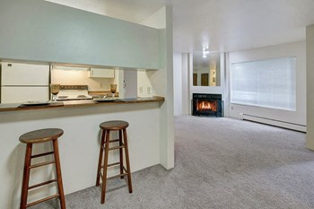A living room with a wide window, fireplace, and breakfast bar Chugach South Living Room - Photo Gallery 2