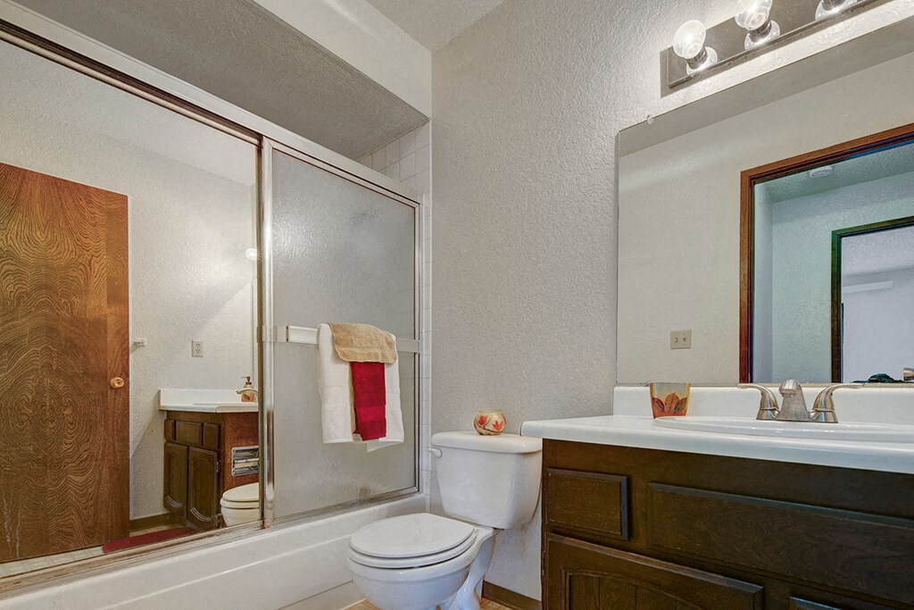 Continental Apartments - Bathroom Modern bathroom here at The Continental Apartments with a tiled shower, glass door, and white sink. A towel hangs over the shower door, and the vanity features a large mirror and lights.