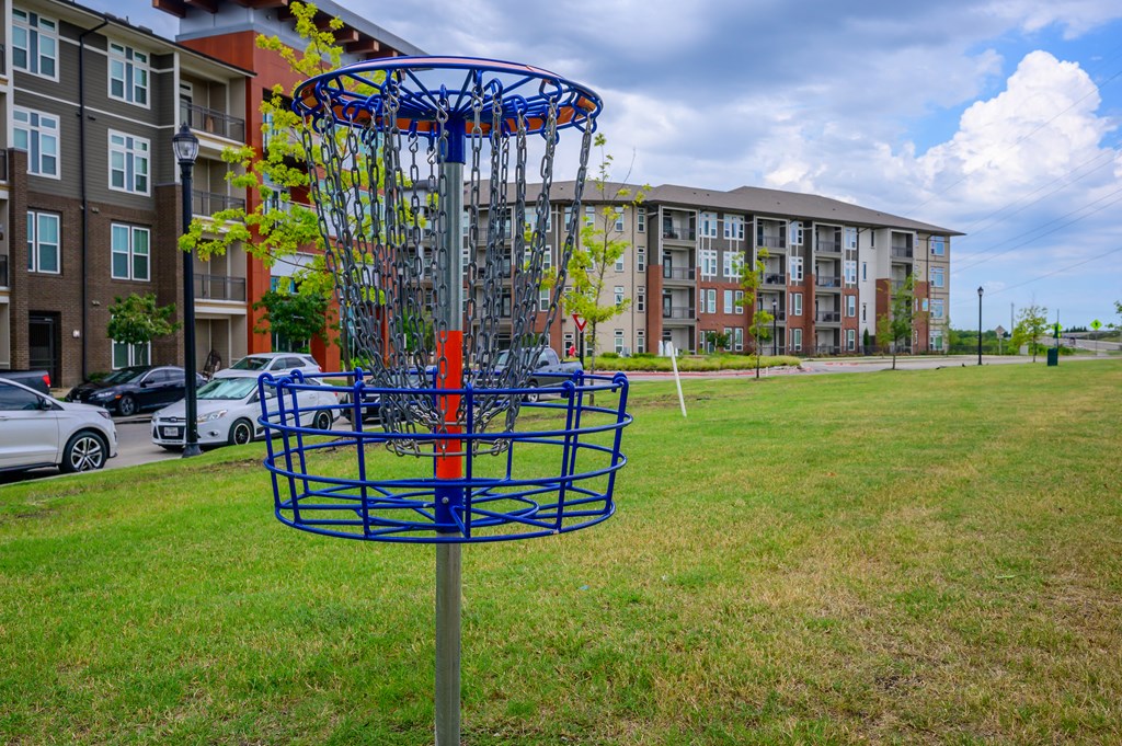 a frisbee hoop in the grass in front of an apartment building