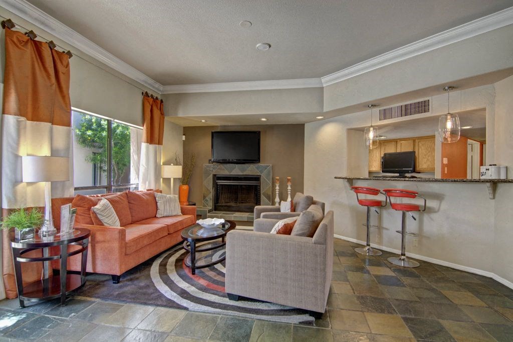 a living room with a fireplace and a kitchen in the background