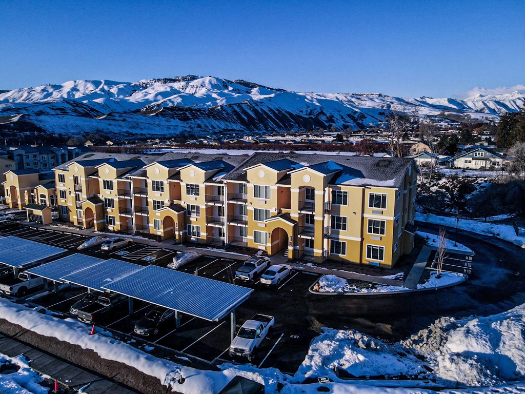 an aerial view of a large apartment complex with snow covered mountains in the background