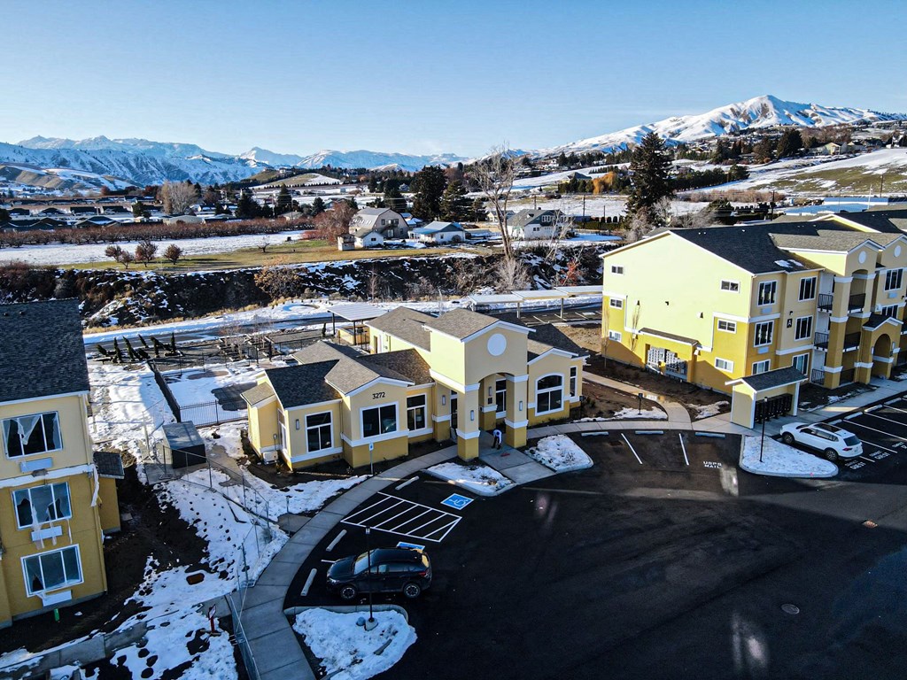 an aerial view of a row of houses with snow covered mountains in the background
