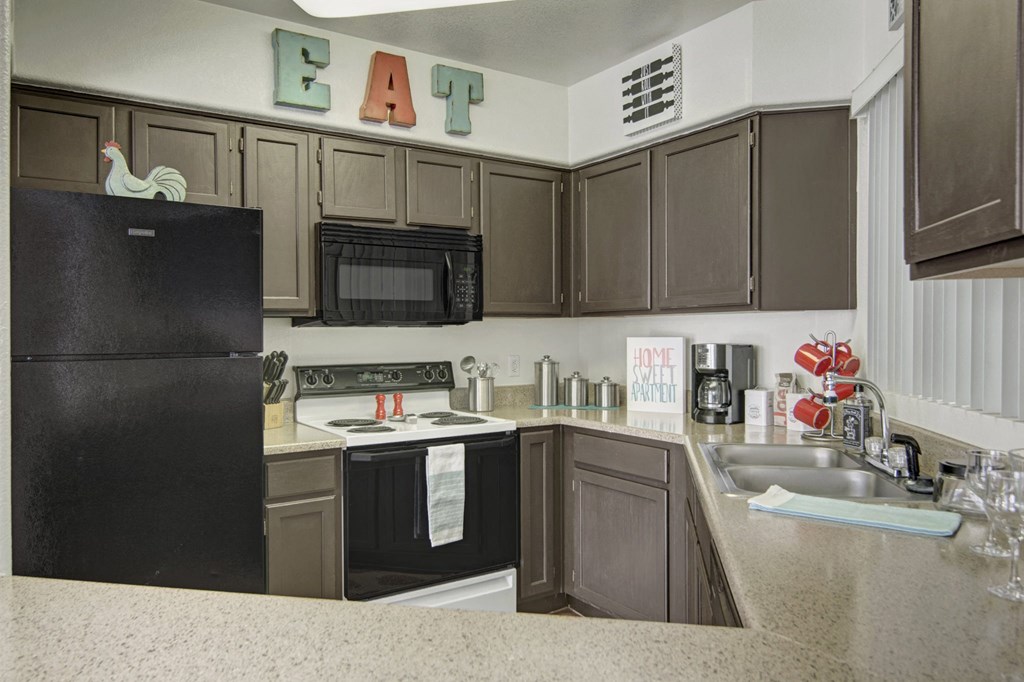 a kitchen with a black refrigerator freezer next to a stove top oven