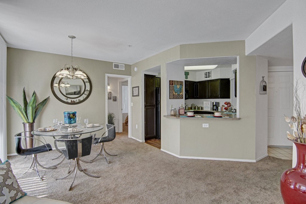 a living room with a table and chairs and a kitchen in the background