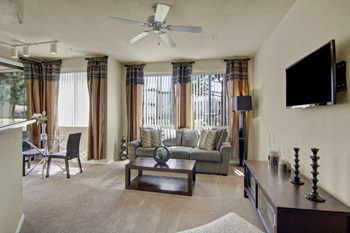 A living room with large windows and a ceiling fan Natura Villas Living Room - Photo Gallery 6