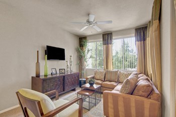 A living room with large windows and a ceiling fan Natura Villas Living Room - Photo Gallery 5