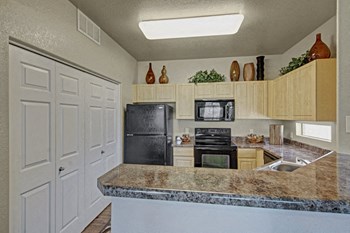 A kitchen with light cabinets and black appliances Natura Villas Kitchen - Photo Gallery 2