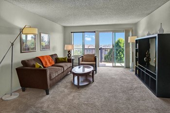 A spacious living room with two sliding glass doors that lead out to the private balcony Overlook at Magnolia Living Room