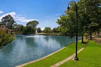 a lake with a fountain and a lamp post in the foreground