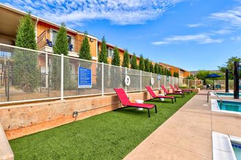 a row of red lounge chairs in front of a chain link fence with a pool in the