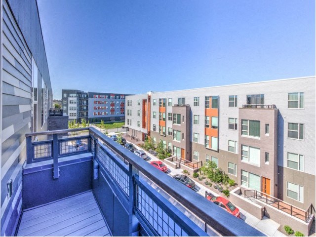 View from a balcony overlooking modern apartment buildings with colorful facades under a clear blue sky at Stitchweld Apartments.