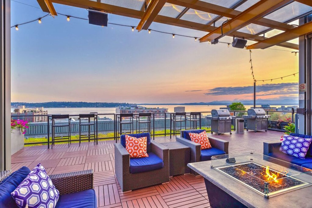 a patio with a firepit and a view of the water