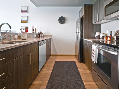 A modern kitchen with dark wood cabinets and stainless steel appliances.