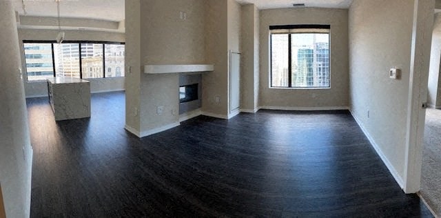 Spacious modern apartment here at Nic on 5th Apartment Homes with dark wood floors, a central fireplace, and large windows offering a cityscape view. Bright and minimalistic design.