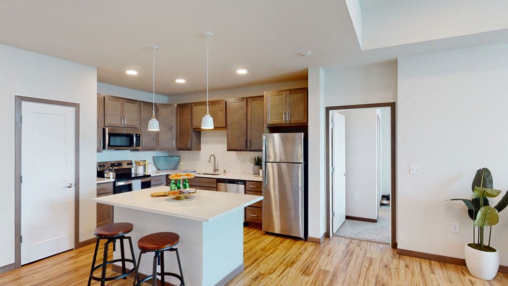 a kitchen with a white island and a stainless steel refrigerator