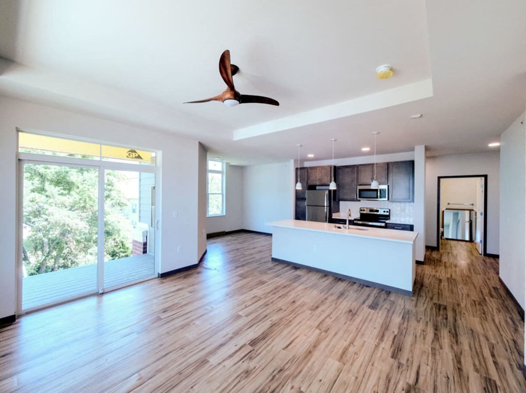 a large living room with a kitchen and a ceiling fan