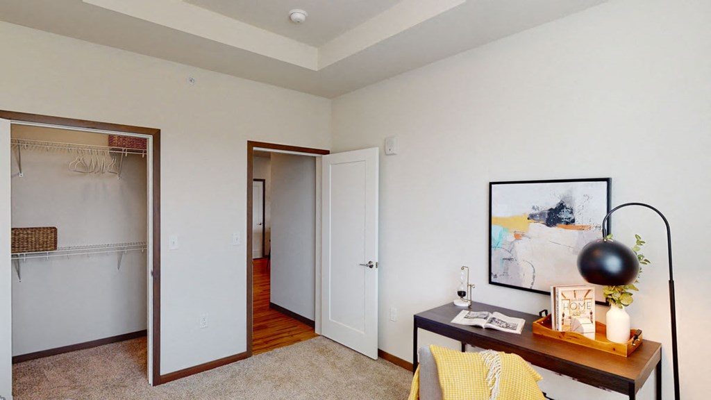 a living room with a desk and a door to a closet