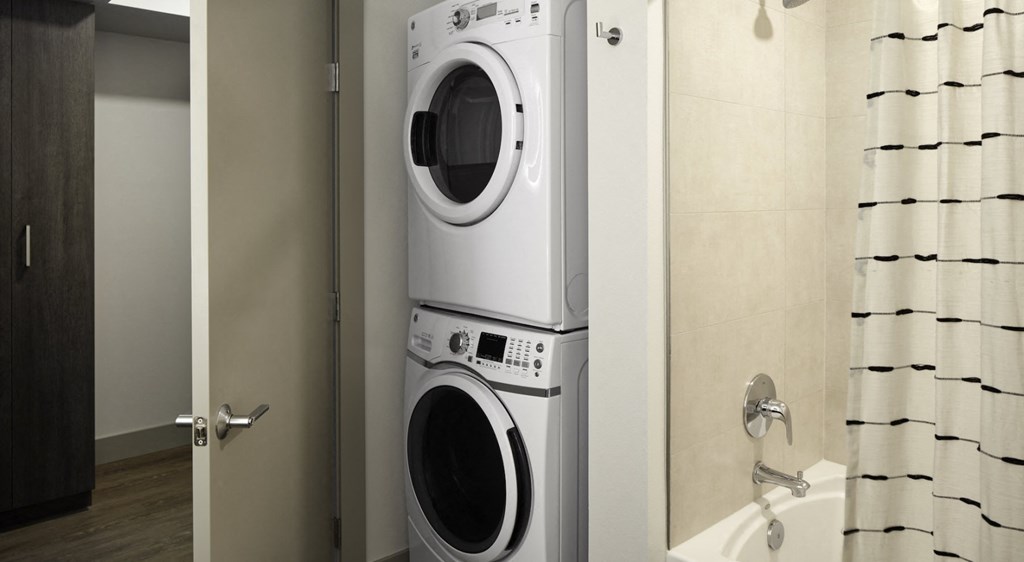 a front loading washer and dryer in a bathroom with a shower curtain