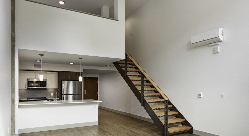 a living room with a staircase and a kitchen