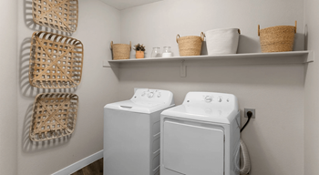 a white washer and dryer in a laundry room with baskets on the wall
