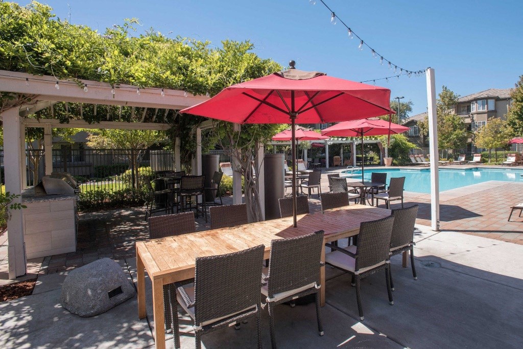 a patio with a pool and tables with umbrellas