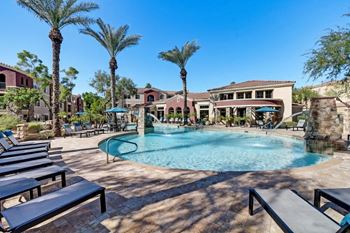 a large swimming pool with benches and palm trees