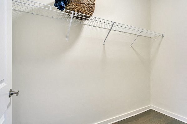 a walk in closet with a basket on top of a rack