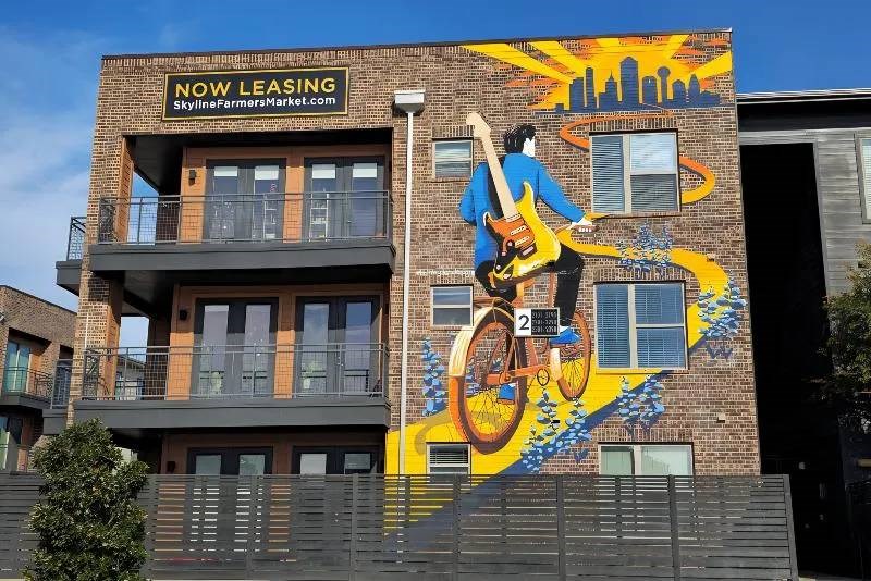 A mural of a man on a bicycle is painted on the side of a building.