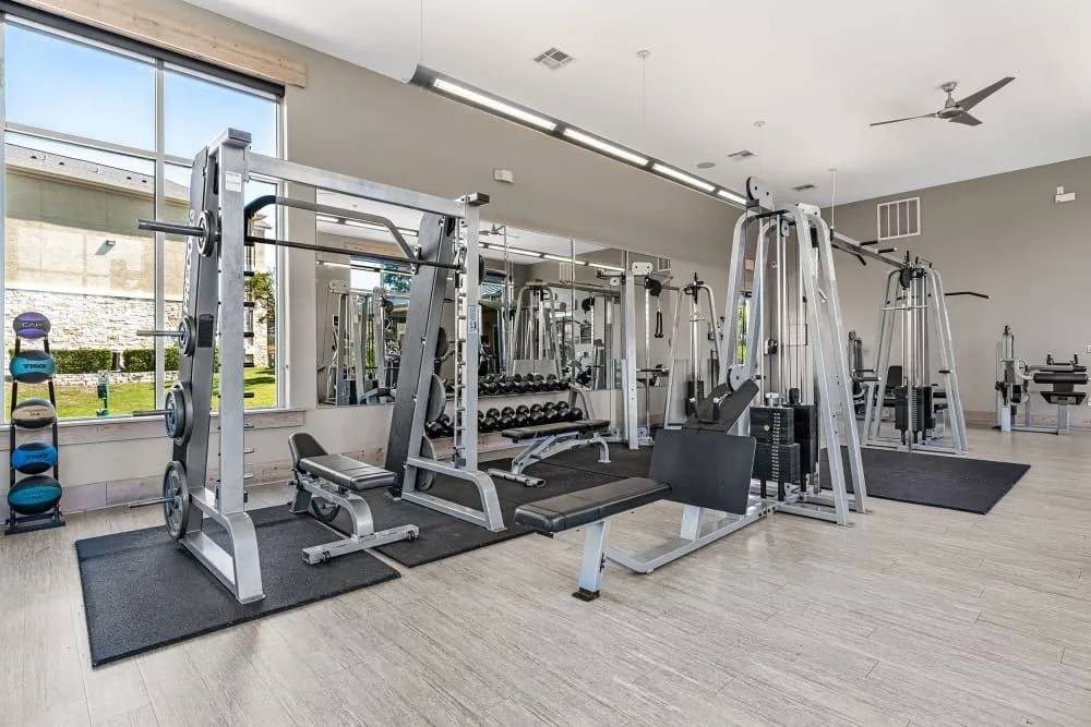 A gym with a variety of equipment including a squat rack, a leg press machine, and a bench press.
