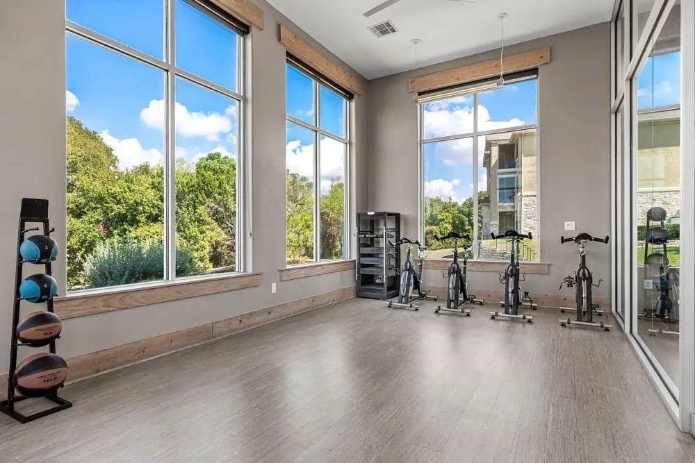 A room with exercise equipment and large windows.