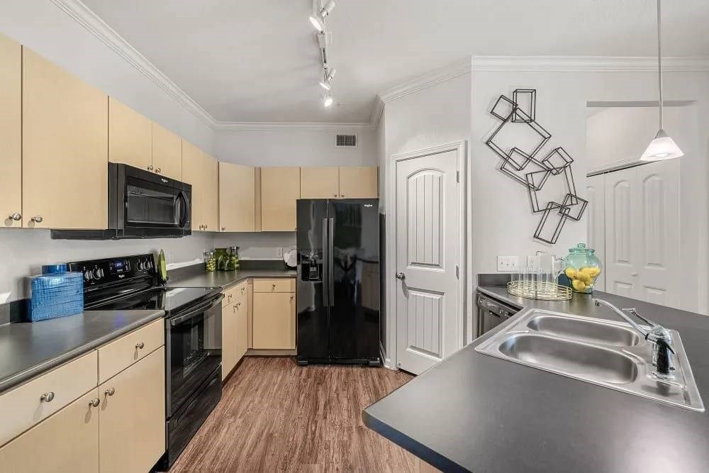 A kitchen with black appliances and wooden cabinets.