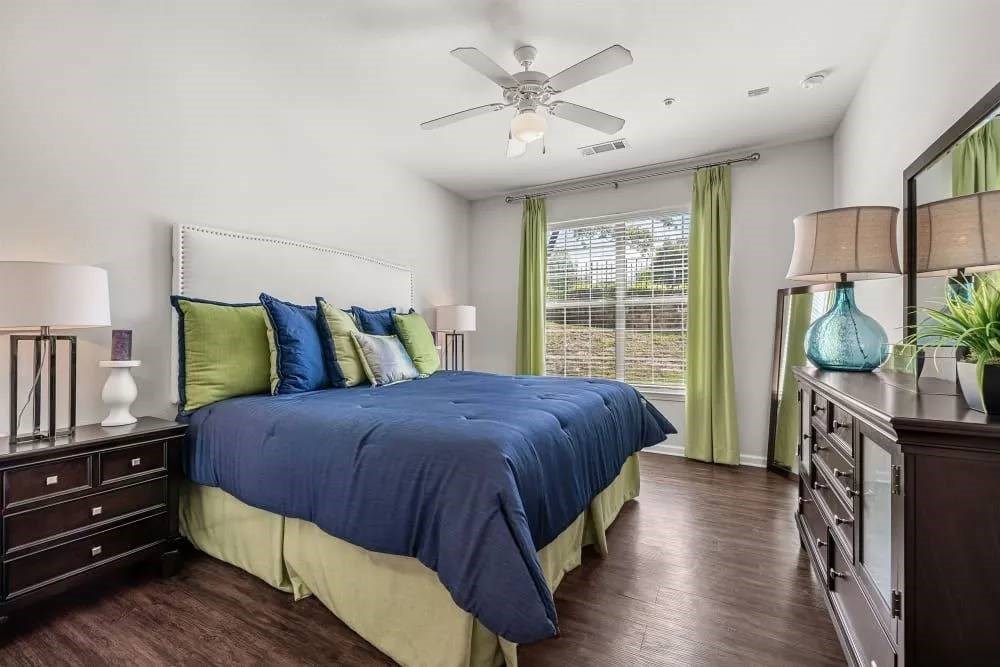 A bedroom with a bed, nightstands, and a ceiling fan.