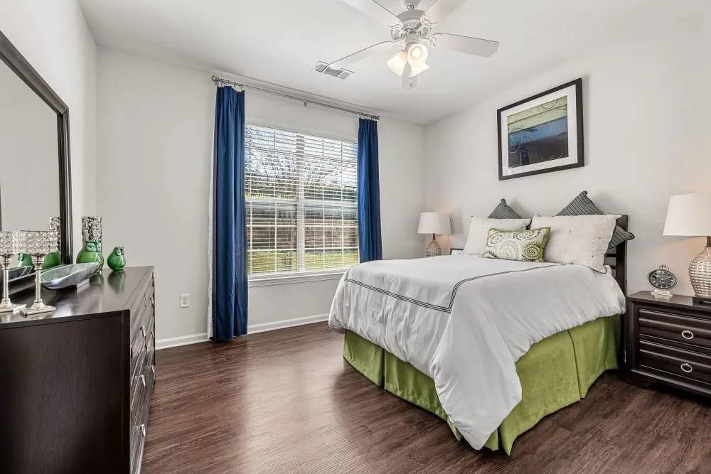 A bedroom with a bed, nightstands, and a ceiling fan.