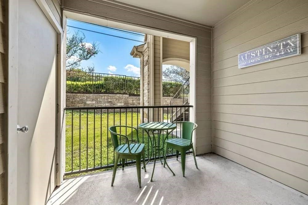 A balcony with a table and chairs overlooking a garden.