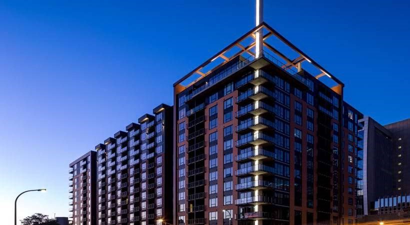 A tall building with a unique design stands under a clear blue sky.