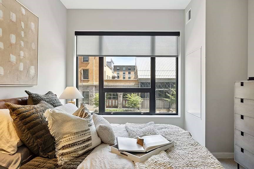 A bedroom with a large bed and a window overlooking a cityscape.