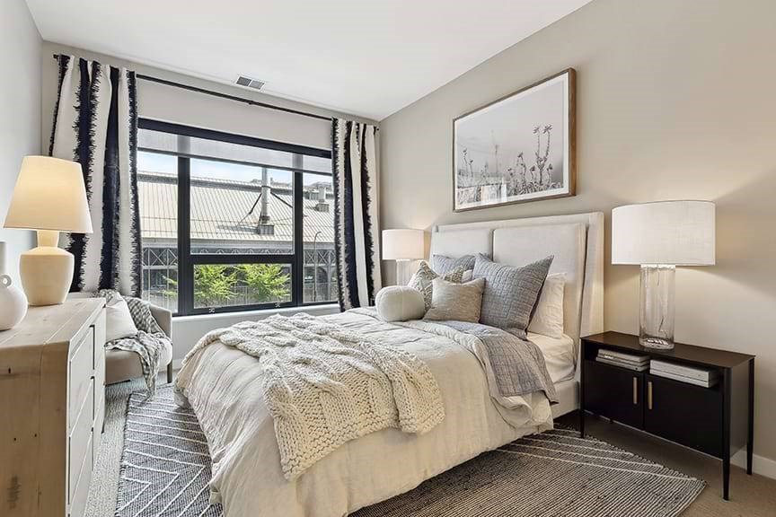 A bedroom with a large bed and a view of a bridge outside the window.