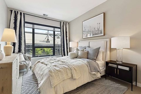 A bedroom with a large bed and a view of a bridge outside the window.
