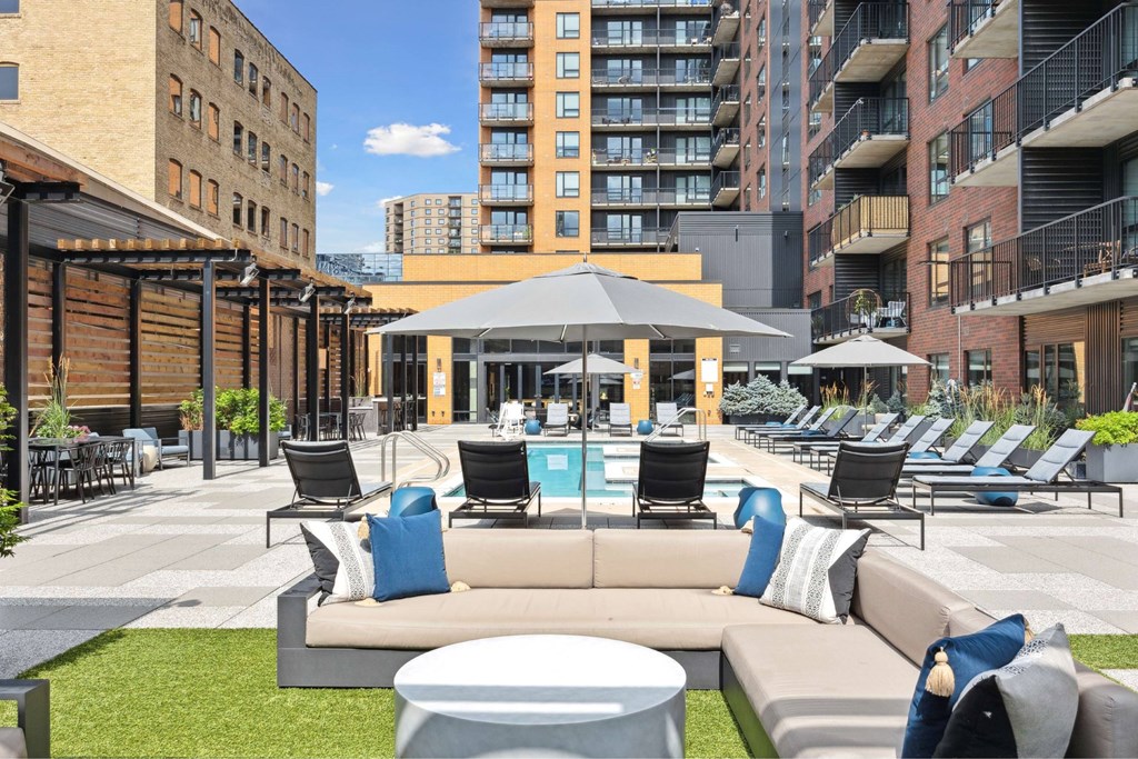 A patio with a pool and lounge chairs.