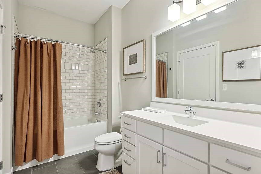 A white bathroom with a brown shower curtain.