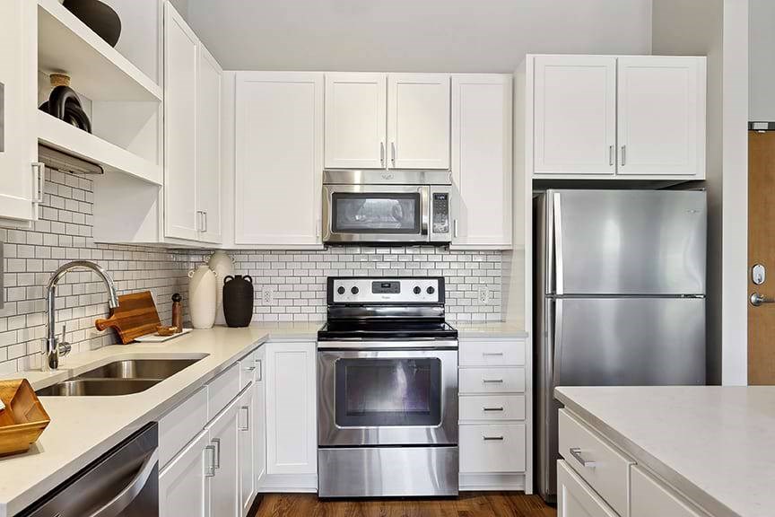 A modern kitchen with white cabinets and stainless steel appliances.