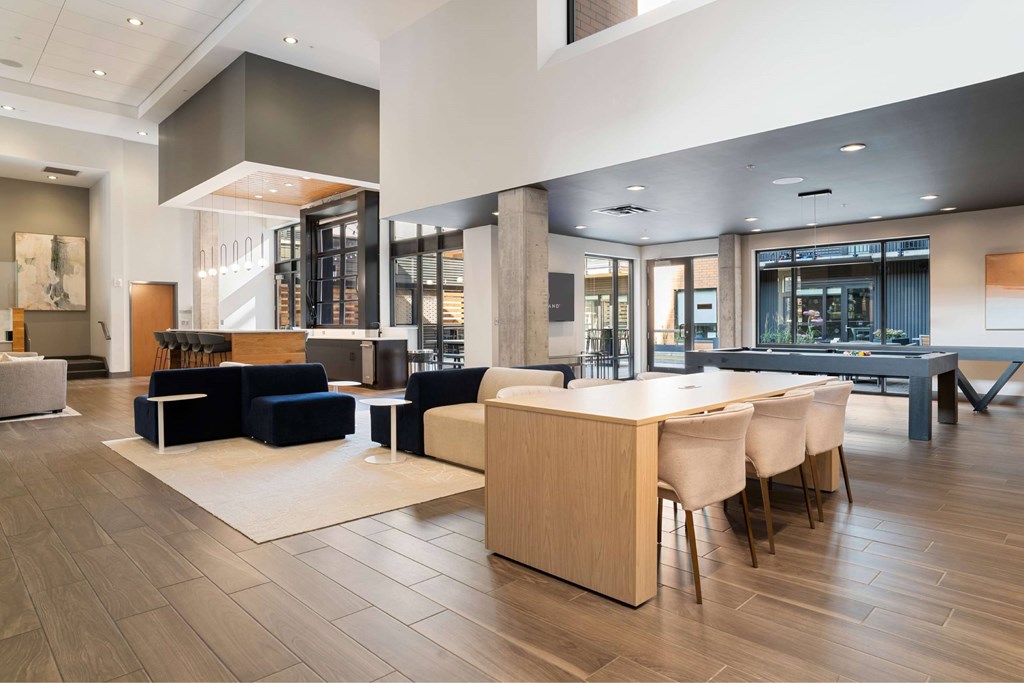 A modern living room with a blue sofa and a wooden dining table.