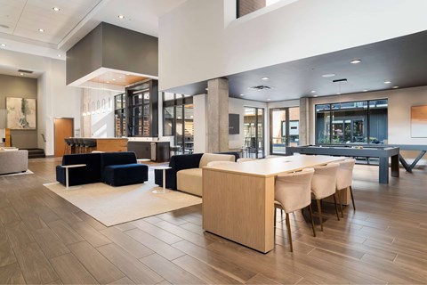 A modern living room with a blue sofa and a wooden dining table.