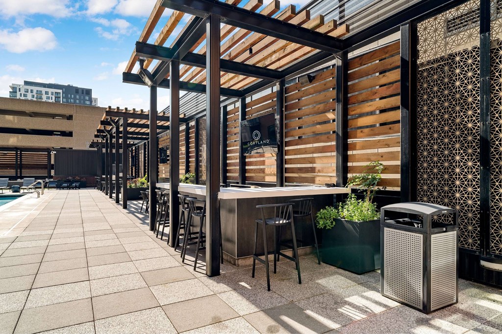 A patio with a table and chairs under a wooden pergola.