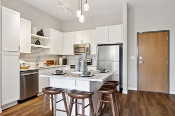 A kitchen with white cabinets and a wooden door.
