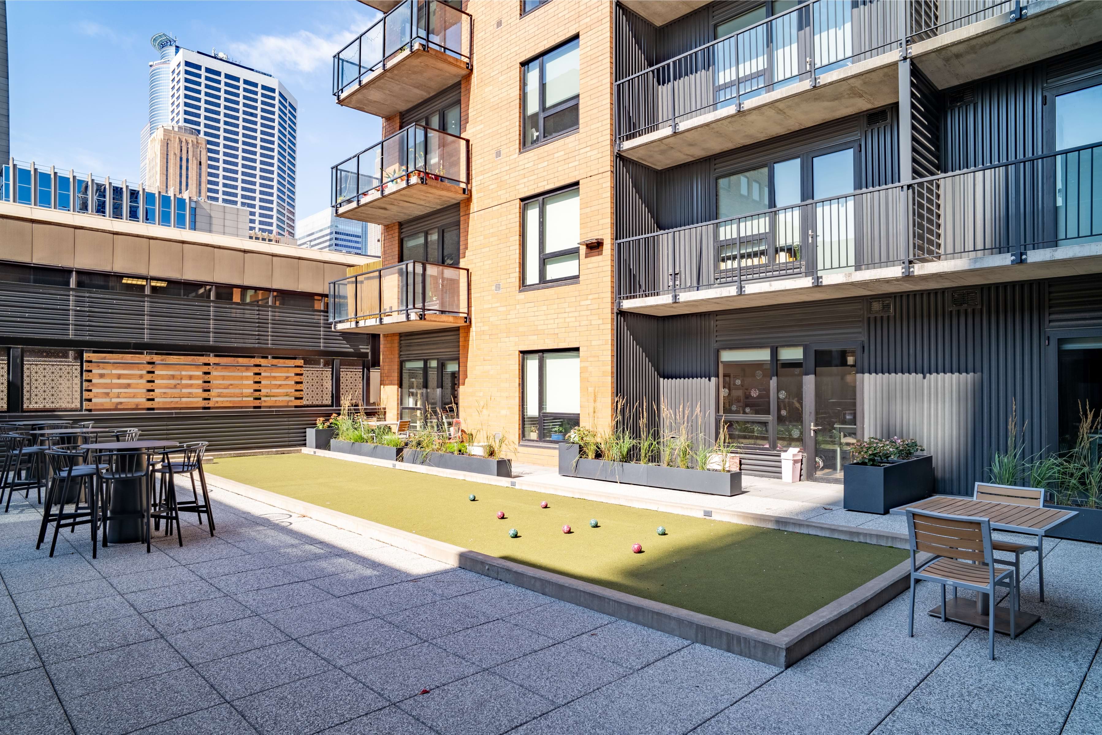 A modern building with a balcony and a small lawn with a table and chairs.