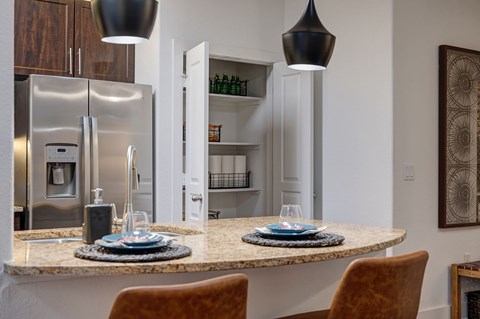 A modern kitchen with a granite countertop and a refrigerator with a water dispenser.